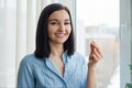 Young woman standing at home near the window taking vitamin Omega 3 fish oil yellow capsule Royalty Free Stock Photo