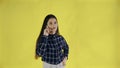 Young woman standing isolated over yellow background while talking by phone Royalty Free Stock Photo