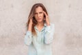 Young woman standing isolated on wall having headache looking camera unhappy