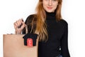 Blak Friday. Young woman standing isolated on white with shopping bag with sale tag close-up blurred background smiling