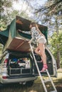 Woman standing in ladder opening tent over car Royalty Free Stock Photo