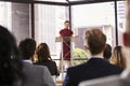 Young woman standing at lectern presenting business seminar