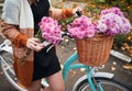 Young woman standing near bicycle with pink flowers. Royalty Free Stock Photo