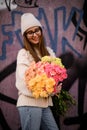 Young woman standing near city wall and holding big and beautiful bunch of fresh carnation flowers in different colors, Royalty Free Stock Photo