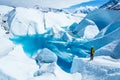 Young woman standing near deep blue lake on the Matanuska Glacier in Alaska. She wears a backpack and helmet with ice axe in hand Royalty Free Stock Photo