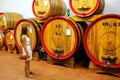 Young woman standing next to wooden barrels at a winery in Monta