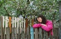 Young woman standing by old fence and smell garden fragrance Royalty Free Stock Photo