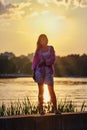 Young woman standing by the river bank in the city during sunset Royalty Free Stock Photo