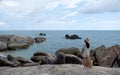 A woman standing on the rock by the seashore with blue sky background Royalty Free Stock Photo