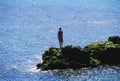 Young woman standing rocks, looking out to sea Royalty Free Stock Photo