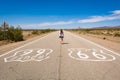 Young woman standing on the Route 66 road in Californian desert.