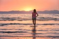 Young woman standing in sea with waves at sunset Royalty Free Stock Photo