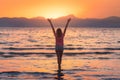 Young woman standing in sea with waves at sunset Royalty Free Stock Photo