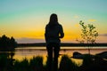 Silhouette of a young woman watching sunset at the lake