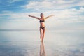 Happy girl with her arms outstretched stands in the water. Beautiful reflection of the cloudy sky in the lake. Young woman Royalty Free Stock Photo