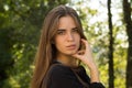 Young woman standing sidewise on the background of trees