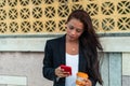 Young woman standing in the street, drinking coffee and using a smartphone. Girl surfing the internet, chatting, blogging. Woman Royalty Free Stock Photo