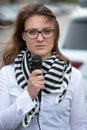 Young woman standing on street with microphone and talking