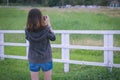 Young woman standing taking photo in a farm behind the fence. Co Royalty Free Stock Photo