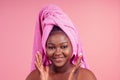 Young woman standing on towel tied on head with hands under chin in studio pink backhround Royalty Free Stock Photo