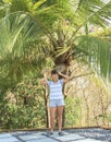 Young woman standing under a palm tree with two leaves Royalty Free Stock Photo