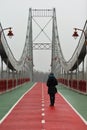 Young woman standing and waiting on a rainy foggy day on the downtown Kyiv pedestrian city bridge