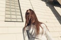 Young woman standing on the wall of the bilding backgroundand looking at camera