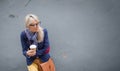 Young woman standing at the wall outdoors and holding a cup of coffee. Royalty Free Stock Photo