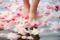 Young woman standing in water feet covered with delicate pink white flowers. Skin care pedicure spa wellness concept Royalty Free Stock Photo