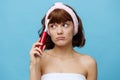 a young woman is standing in a white towel facing the camera, holding a red toothbrush in her hand and looking at it Royalty Free Stock Photo