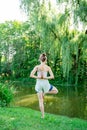 Young woman standing in yoga pose on one leg with hands as in prayer near river Royalty Free Stock Photo