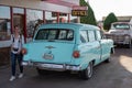 Young woman stands beside a blue Ford Ranch Wagon parked in front of a retro diner