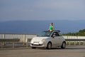 Woman traveller enjoys rocky landscapes above clouds high in mountains from small convertible car. Royalty Free Stock Photo