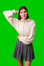 Young Woman Posing With Hand on Head Against a Vibrant Green Background