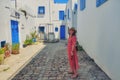 A young woman stands in the courtyard with blue windows and doors with Arabic ornaments. Texture of Islamic symbols in Sidi Bou