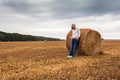 A young woman stands on the field, leaning on a sheaf of hay. Royalty Free Stock Photo