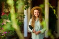 Young woman stands in garden holding gardening tool in her hands smiles and looks at camera. Junior female gardener with Royalty Free Stock Photo