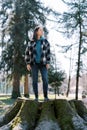 Young woman stands on a huge stump covered with moss and looks away