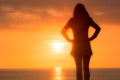 Young woman stands looking out to sea at the sunset Royalty Free Stock Photo