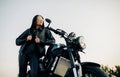 Young woman stands near black motorbike against sky background Royalty Free Stock Photo