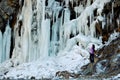 A young woman stands near a frozen waterfall