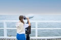 A young woman stands on the pier, looking through coin binoculars. Royalty Free Stock Photo