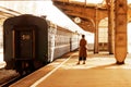 A young woman stands on the platform under the station clock