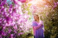 Young woman stands, resting and enjoying the spring blooming garden among the rhododendron flowers in the sunlight Royalty Free Stock Photo