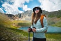 young woman stands on a rock and looks to the side, near a lake in the autumn mountains. Mountain lake and traveler with Royalty Free Stock Photo