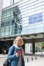 A young woman stands with a telephone in her hands opposite the European Parliament building in Brussels, Belgium. Royalty Free Stock Photo