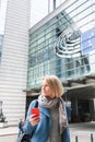 A young woman stands with a telephone in her hands opposite the European Parliament building in Brussels, Belgium. Royalty Free Stock Photo