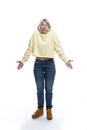 A young woman stands and throws up her hands in surprise. Blonde in a yellow sweater and jeans. Full height. Isolated on white