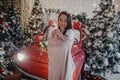 Woman stands near Christmas tree and retro car against background of snowfall Royalty Free Stock Photo