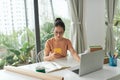 A young woman starting an online business works on her laptop and waits for orders